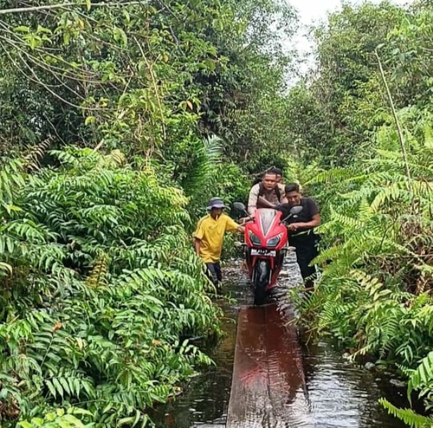 Bhabinkamtibmas di Tebingtinggi Timur Ini Bantu Warga Melintasi Jalan Terendam Banjir
